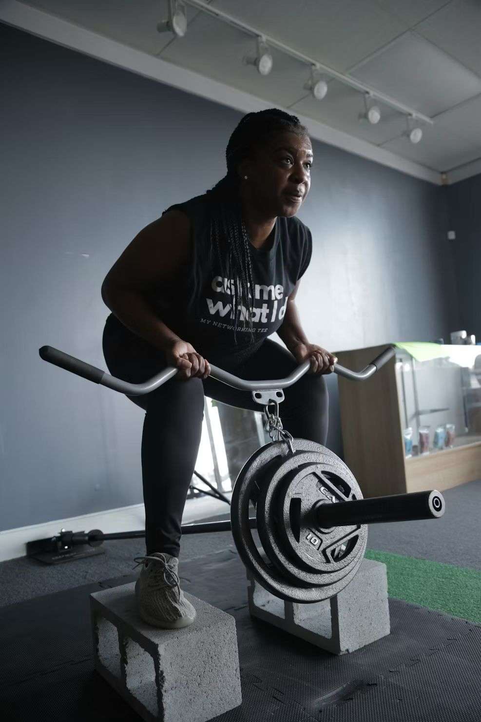 Woman performing a belt squat with weight plates between two concrete blocks